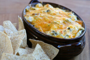 Spinach Artichoke Dip Recipe in brown baking dish with homemade corn tortilla chips