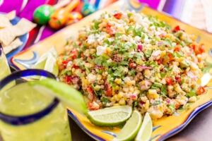 Mexican street corn salad with grilled corn in large serving dish.