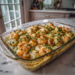 Glass baking dish filled with healthy shrimp pierogi casserole topped with parsley on a white marble countertop in a bright kitchen.
