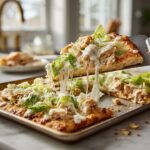 High protein rotisserie chicken Caesar flatbread with shredded chicken, romaine lettuce, parmesan cheese and creamy Caesar dressing on a white marble countertop