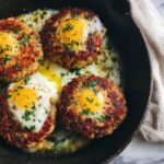 Crispy turkey and black bean protein cakes cooked in a skillet with eggs cracked into the centers and runny yolks.